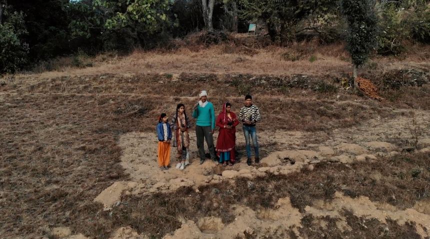 Family standing on their farmland with saplings